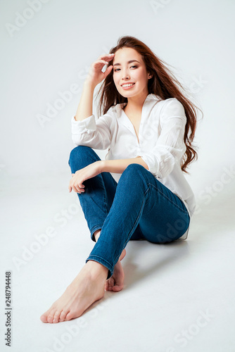 Beauty fashion portrait of smiling sensual asian young woman with dark long hair in white shirt on white background