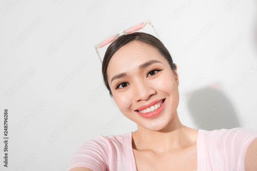 Close-up of young beautiful woman taking selfie. Isolated white background Close-up of young beautiful woman taking selfie. Isolated white background