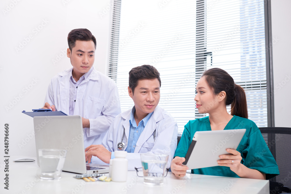 Group of doctors and nurses examining medical report of patient. Team of doctors working together on patients file at hospital. Group of doctors and nurses examining medical report of patient. Team of doctors working together on patients file at hospital.