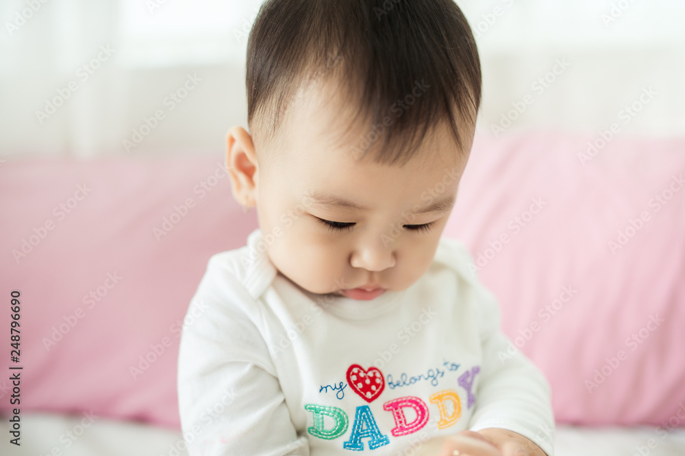 Lovely asian baby girl sitting on bed at her room. Lovely asian baby girl sitting on bed at her room.