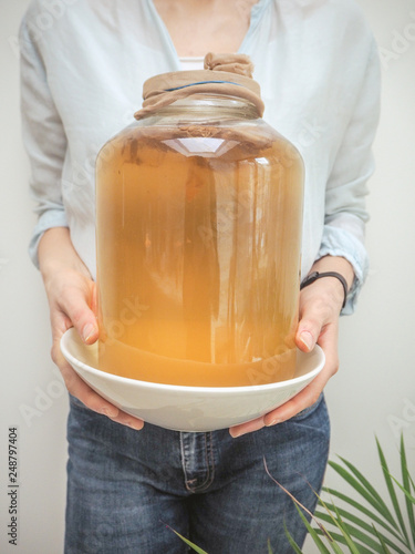 Caucasian woman holding a big jar with homemade kombucha tea photo