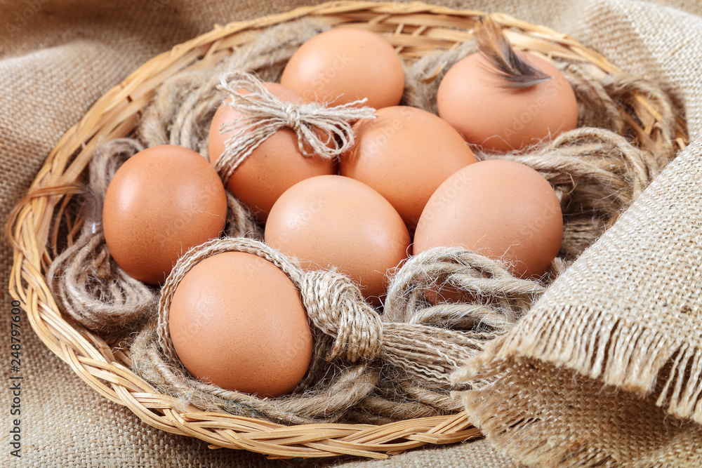Chicken eggs in a wicker basket on canvas Chicken eggs in a wicker basket on canvas