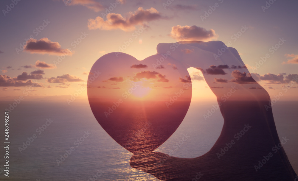 Love is happiness. Hand holding heart against sunset.  - obrazy, fototapety, plakaty 