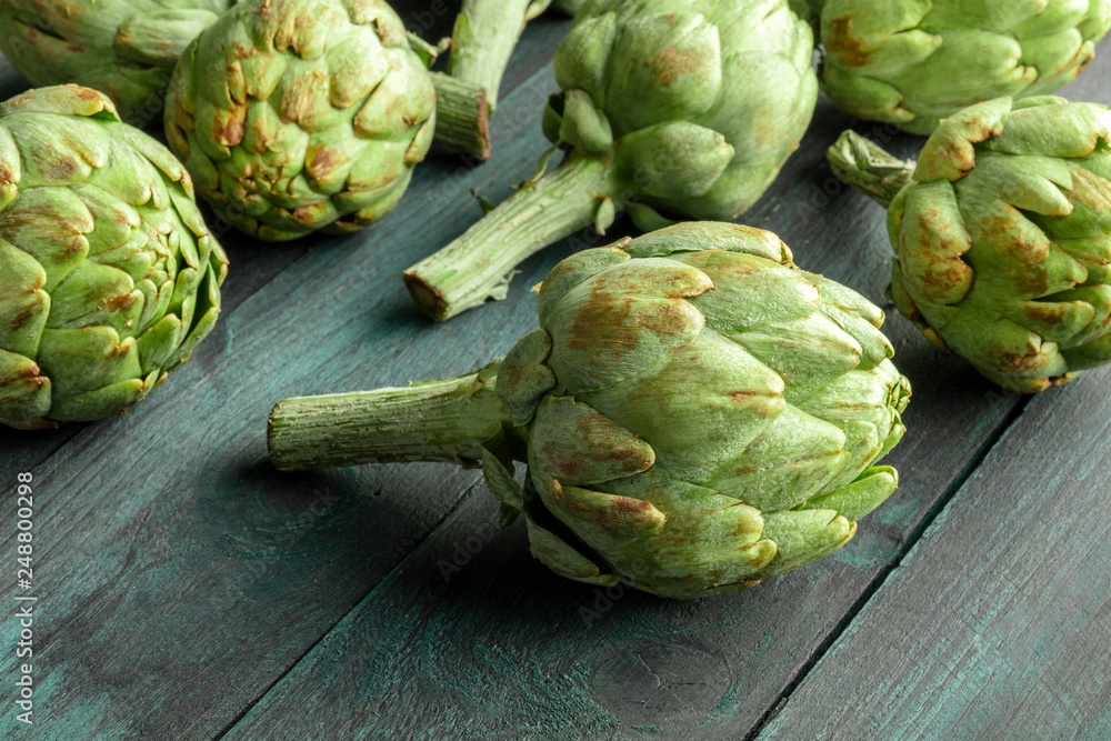 A closeup of a globe artichoke on a dark rustic wooden background with a place for text A closeup of a globe artichoke on a dark rustic wooden background with a place for text