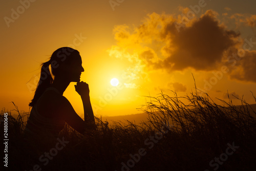 silhouette of happy woman in field watching the sunset