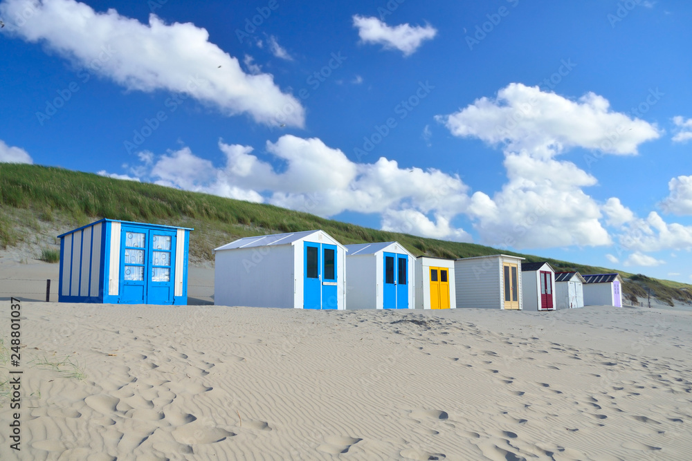 Naklejka premium Row of colorful wooden beach sheds on the beach of island Texel in the Netherlands