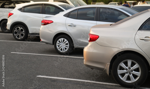 Closeup of back or rear side of golden car and other cars parking in parking area in twilight evening. 