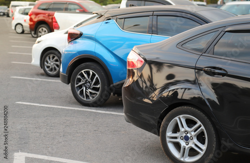 Closeup of back or rear side of black car and other cars parking in parking area in twilight evening.