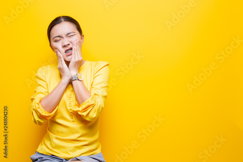 Woman has toothache isolated over yellow background