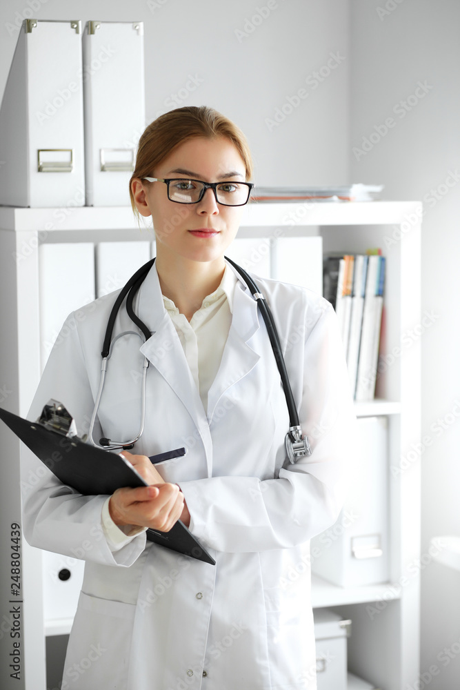 Doctor woman at work. Portrait of female physician using clipboard at hospital office. Medicine and healthcare concept Doctor woman at work. Portrait of female physician using clipboard at hospital office. Medicine and healthcare concept
