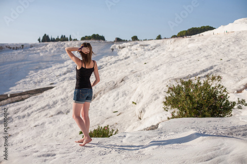 Natural travertine pools and terraces in Pamukkale. Cotton castle in southwestern Turkey, girl standing in natural pool. A woman in the pool of thermal springs and travertine 