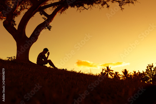 silhouette of a man praying at sunset