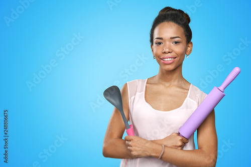 African american woman holding kitchen utensils