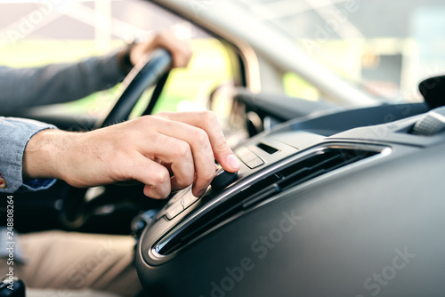 Close up of man changing radio station while driving car. © dusanpetkovic1