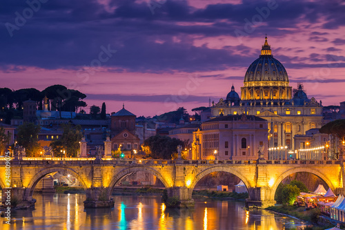 Night view of old Sant' Angelo Bridge and St. Peter's cathedral in Vatican City Rome Italy.