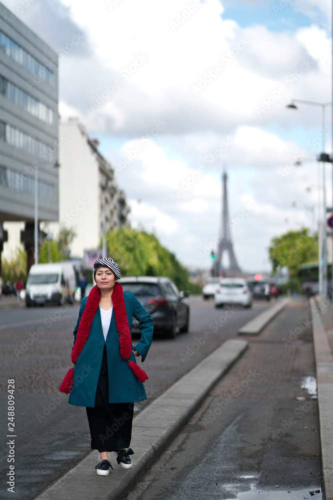 Fototapeta premium Femme marchant dans la rue avec tour eiffel en arrière plan