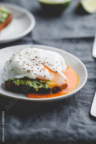 Avocado sandwich with rye bread and a poached egg on a plate. The concept of healthy balanced breakfast.