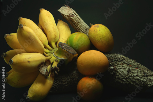 Thai banana and orange on timber on back background for decoration.