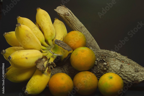 Thai banana and orange on timber on back background for decoration.