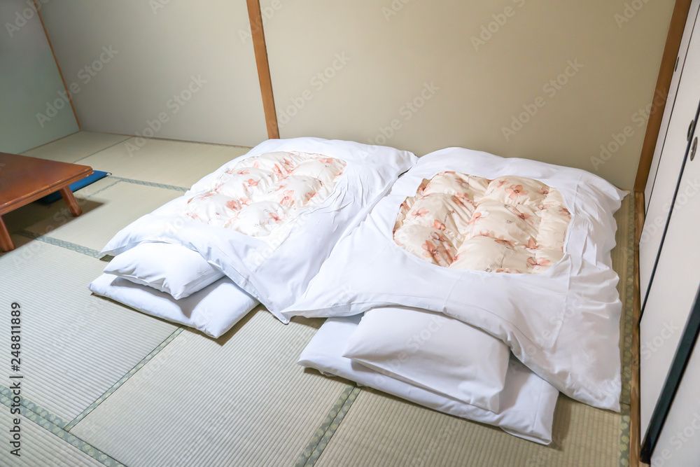Futon; a Japanese quilted mattress rolled out on the floor (tatami) for use  as a bed., Japan style. Stock Photo