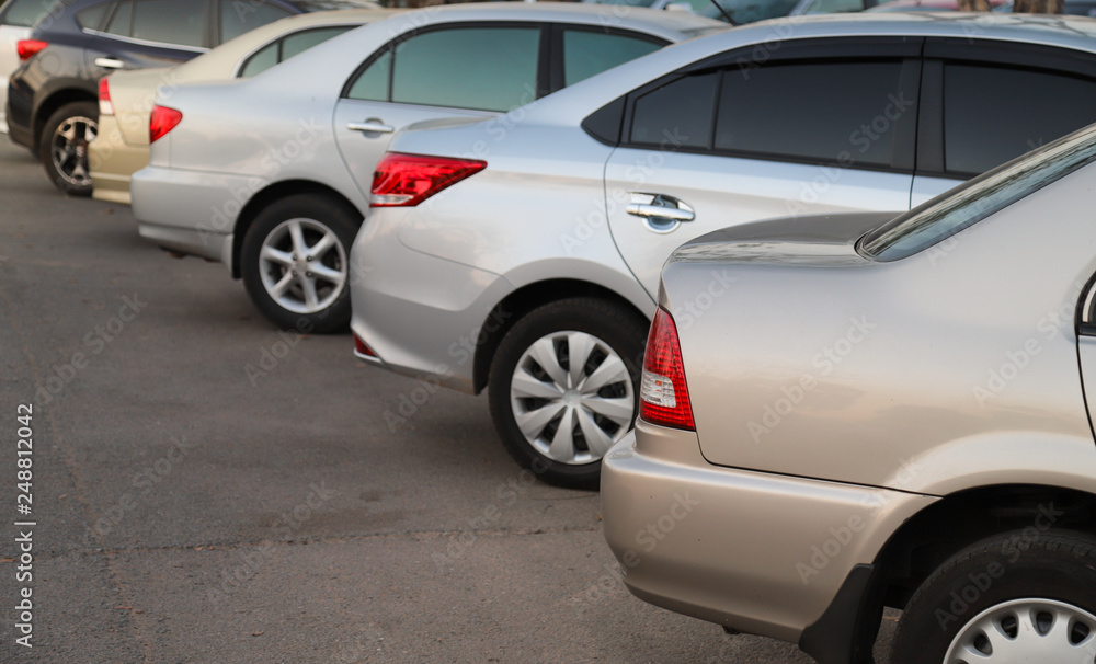 Closeup of rear or back side of golden car with  other cars parking in parking area in the evening. 