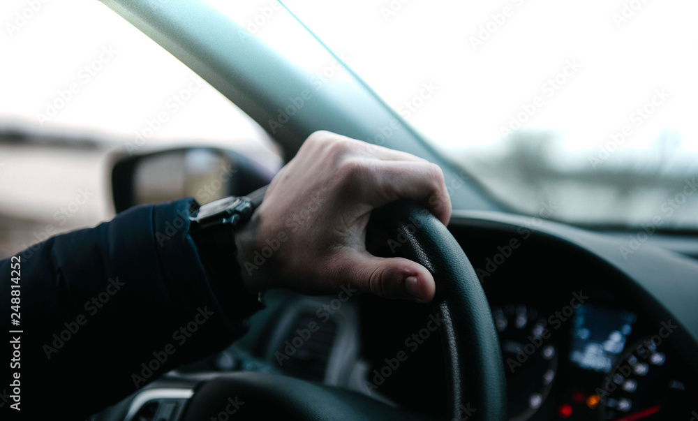 A young man driving an auto. A man sits inside a car in the driver's seat A young man driving an auto. A man sits inside a car in the driver's seat