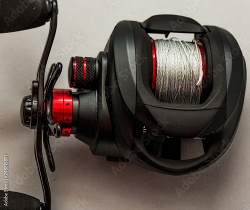 Close up of baitcasting reel loaded with braided mainline isolated against a white background photo