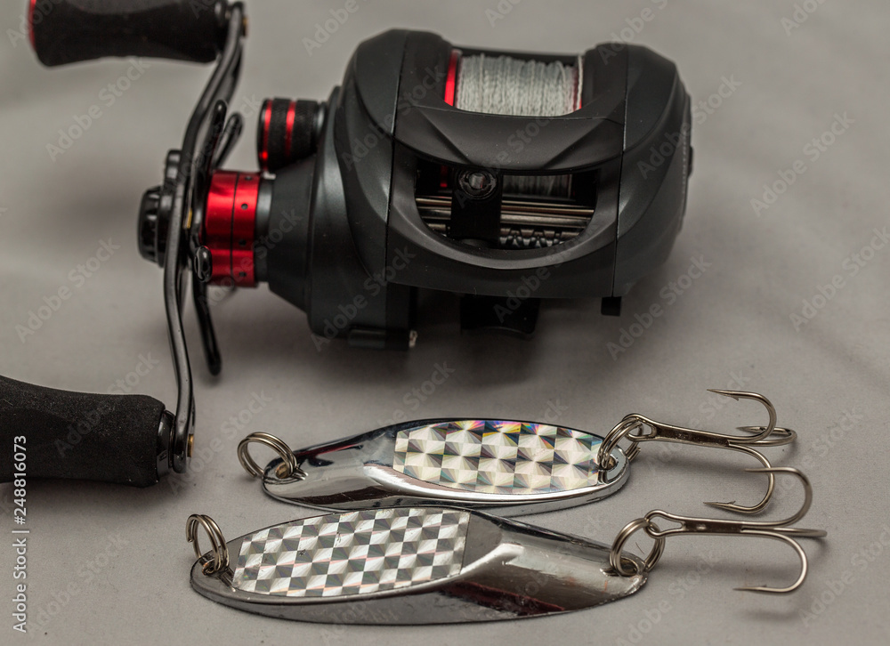 Close up of bait caster fishing reel and metal bass lures Stock