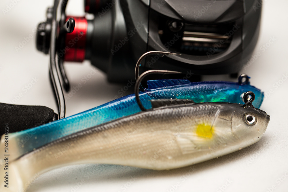 Close up of unidentifiable bait caster fishing reel and rubber fishing lures  Stock Photo