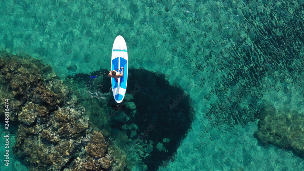 Aerial drone top down photo of man exercising sup board in turquoise tropical clear waters