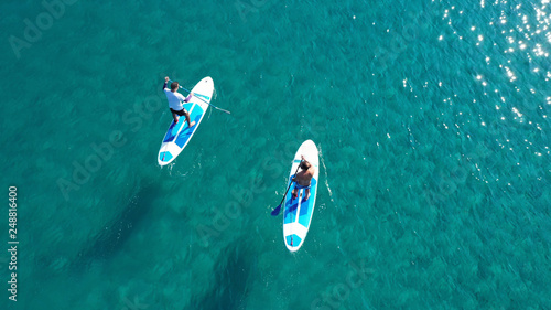 Slika na platnu Aerial drone bird's eye view of 2 men exercising sup board in turquoise tropical