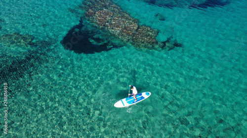 Aerial drone bird's eye view of 2 men exercising sup board in turquoise tropical clear waters