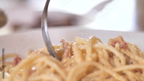 Child's hands try to use fork taking spagetthi carbonara into his plate, slow motion. photo