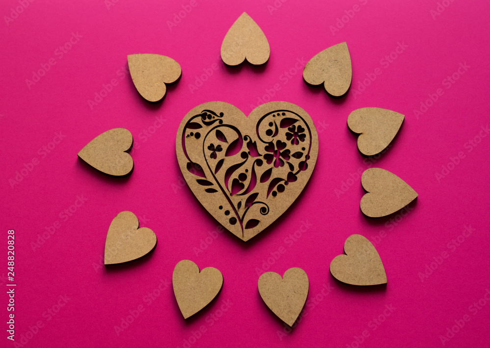 Fototapeta premium Sunny hearts composition from top view on pink background. Poker-drawing wooden heart in the center.