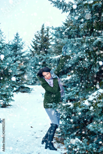beautiful woman is in winter forest, green fir trees with snow