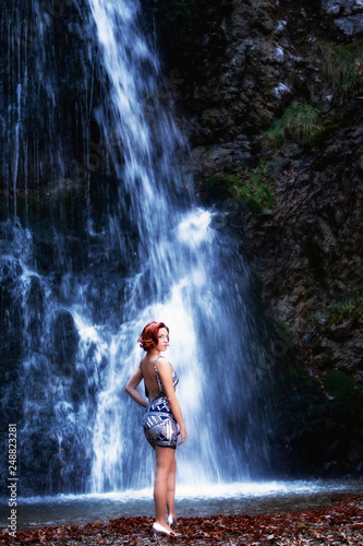 Rothaarige Frau vor einem Wasserfall