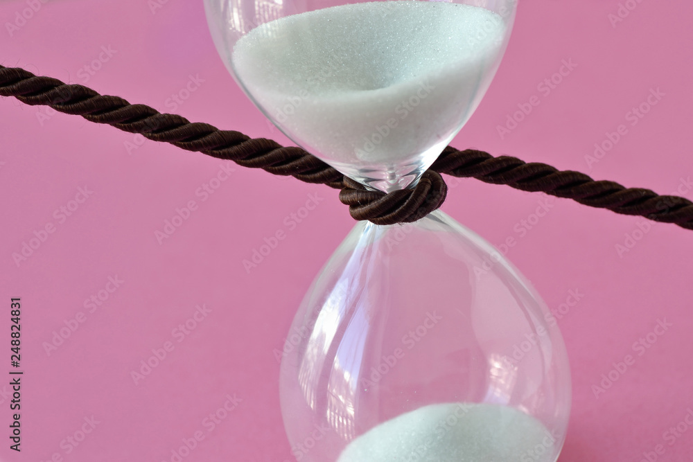 Εκτύπωση καμβά Close-up of hourglass with a cord around it on pink background - Stop the time c
