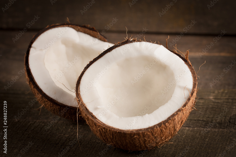 Ripe half cut coconut on a wooden background. Coconut cream and oil. Ripe half cut coconut on a wooden background. Coconut cream and oil.