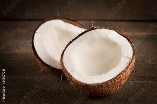 Ripe half cut coconut on a wooden background. Coconut cream and oil.