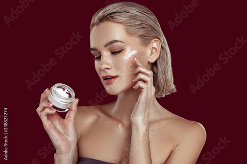 Model working for cosmetics brand putting some cream on her face