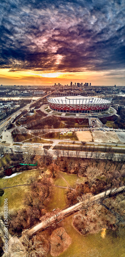 Beautiful panoramic aerial drone view to panorama of Warsaw modern City with skyscraper and The PGE Narodowy National Stadium (Polish: Stadion Narodowy) against the background of a dramatic sunset © udmurd