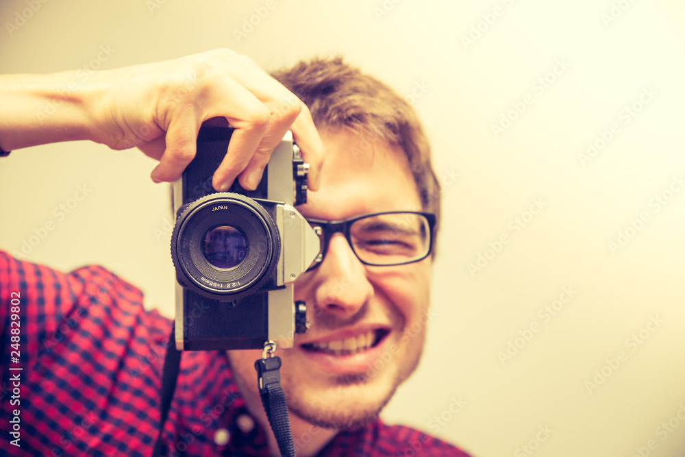 Fototapeta premium Young man is taking a picture with a vintage camera