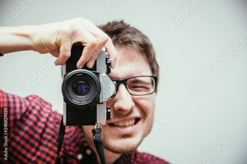 Young man is taking a picture with a vintage camera
