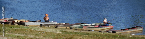 Two fishermen sitting on the boats fishing with protection from sun like umbrella