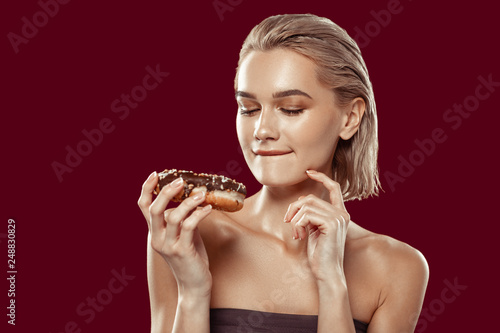 Close up of woman hesitating while looking at sweet doughnut