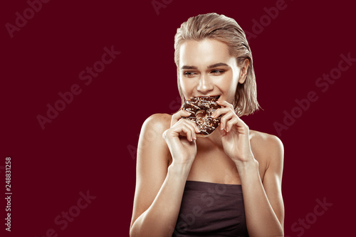 Slim appealing woman eating sweet chocolate doughnut