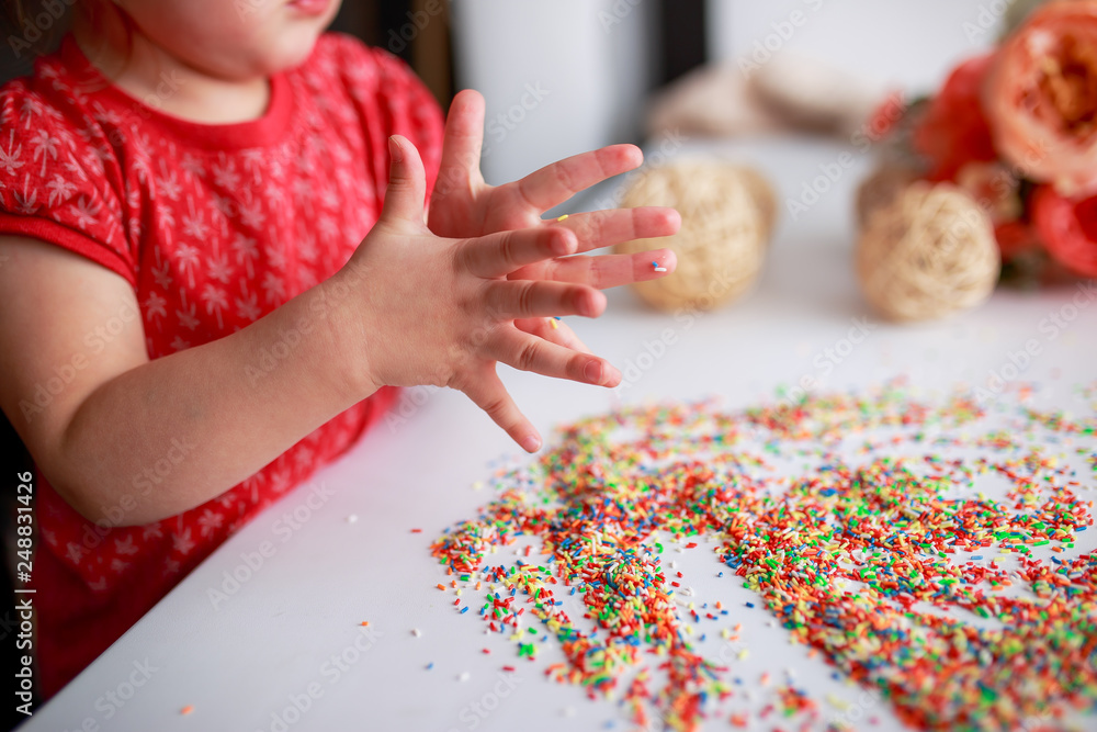Baby hands in sugar topping. Baby drawing. Baby fingers with candies. Easter sugar topping. Baby hands in sugar topping. Baby drawing. Baby fingers with candies. Easter sugar topping.