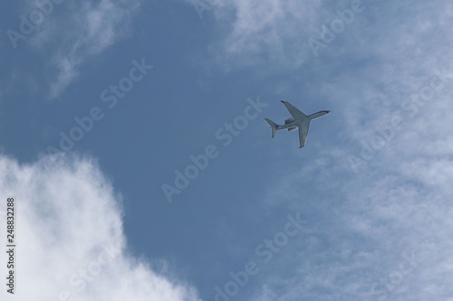 A passenger airplane flying high in the sky among the clouds. Air liner leaving a trace of exhaust gases glowing in the sun. Ecology of passenger traffic. Transport of goods by air.