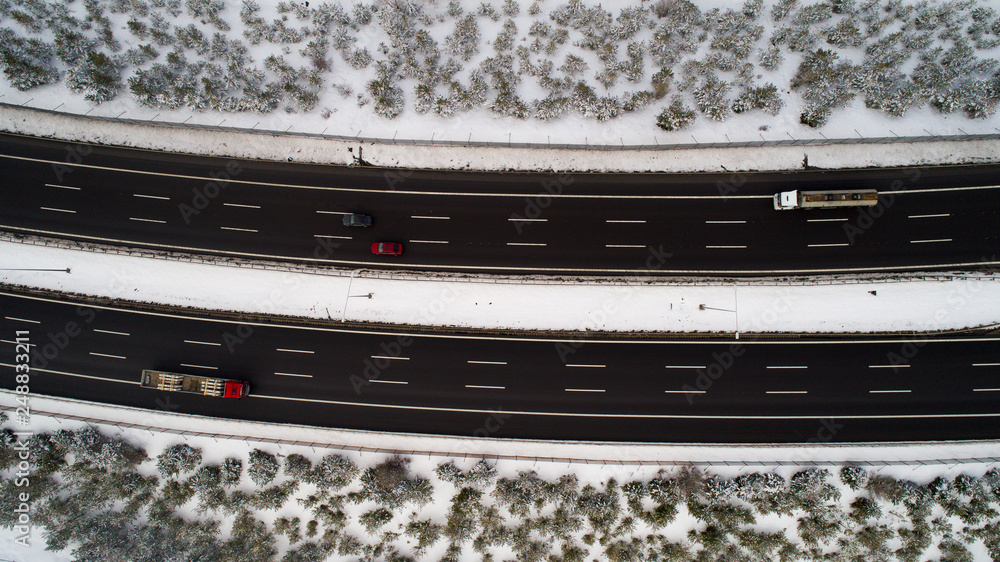 Aerial view of winter asphalt highway or motorway road in countryside with cars and cargo logistic trucks in winter time Aerial view of winter asphalt highway or motorway road in countryside with cars and cargo logistic trucks in winter time