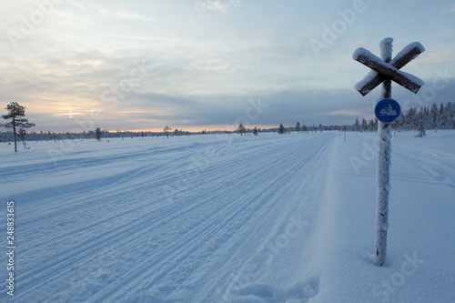 Frozen snowmobile track in a cloudy sunset, Lapland in Finland. 